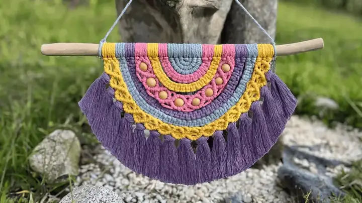 Tapiz artesanal de macramé en amarillo, rosa, azul y violeta